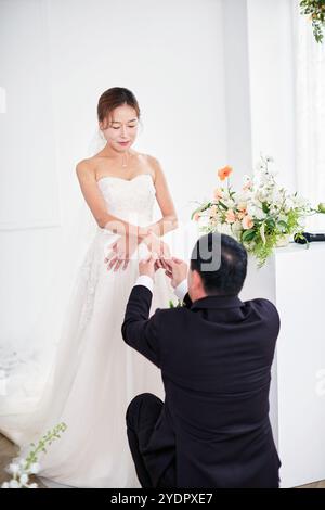 Petit mariage - le prêtre est présent, la mariée et le marié tiennent leurs bouquets de mariage, se tiennent la main et partagent un beau moment avec la famille et les amis Banque D'Images