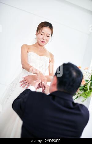 Petit mariage - le prêtre est présent, la mariée et le marié tiennent leurs bouquets de mariage, se tiennent la main et partagent un beau moment avec la famille et les amis Banque D'Images