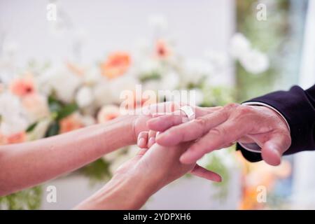 Petit mariage - le prêtre est présent, la mariée et le marié tiennent leurs bouquets de mariage, se tiennent la main et partagent un beau moment avec la famille et les amis Banque D'Images