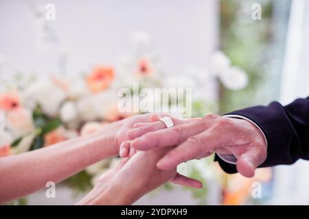 Petit mariage - le prêtre est présent, la mariée et le marié tiennent leurs bouquets de mariage, se tiennent la main et partagent un beau moment avec la famille et les amis Banque D'Images