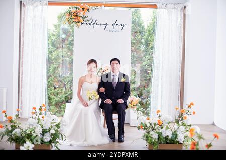 Petit mariage - le prêtre est présent, la mariée et le marié tiennent leurs bouquets de mariage, se tiennent la main et partagent un beau moment avec la famille et les amis Banque D'Images