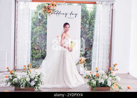 Petit mariage - le prêtre est présent, la mariée et le marié tiennent leurs bouquets de mariage, se tiennent la main et partagent un beau moment avec la famille et les amis Banque D'Images