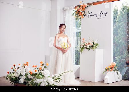 Petit mariage - le prêtre est présent, la mariée et le marié tiennent leurs bouquets de mariage, se tiennent la main et partagent un beau moment avec la famille et les amis Banque D'Images