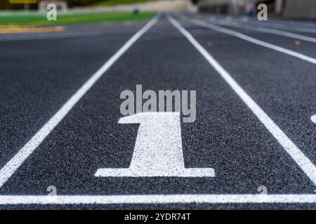 Fermez la voie numéro 1 sur une nouvelle piste de course noire avec des lignes de voie blanches et d'autres marquages. Banque D'Images