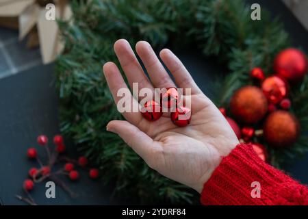 Couronne de Noël faite à la main à partir de décorations rouges festives. Classe de maître artisanale de préparation de vacances festives de décoration créative. Activités pratiques création d'ateliers cadeaux de fêtes responsables et durables. Vue de dessus, pose à plat Banque D'Images