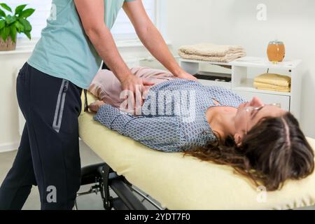 Jeune femme souffrant de mal de dos en physiothérapie. Chiropraticien examinant la patiente. Banque D'Images