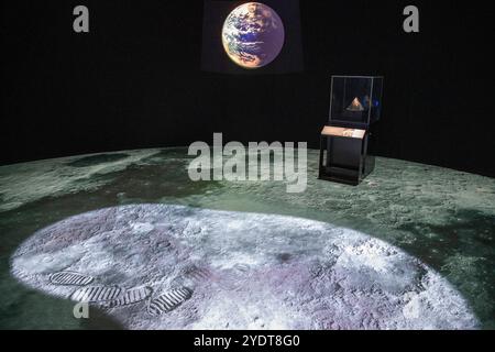 Une exposition sur le thème de la lune présentant une projection de la surface lunaire avec des empreintes d'astronautes, un modèle de la Terre en arrière-plan. Banque D'Images