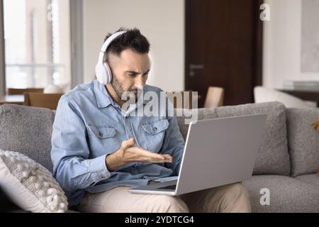 Nerf confus latin freelance homme dans des écouteurs regardant l'ordinateur portable Banque D'Images
