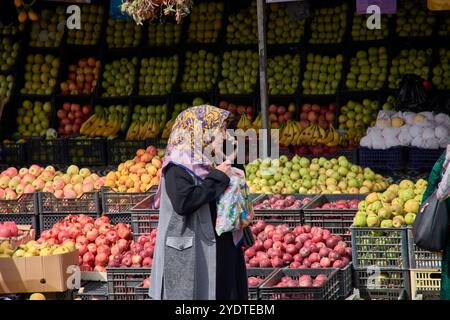 Tachkent, Ouzbékistan;septembre,16,2024:une femme musulmane âgée portant un hijab traditionnel est capturée parlant sur son téléphone alors qu'elle marchait Banque D'Images