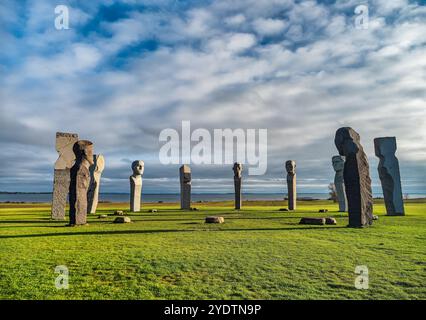 Dodekalitten de grandes sculptures en pierre se dressent majestueusement sur un champ herbeux au bord de la côte, sous un ciel vibrant. Ce cadre serein évoque mystère et con Banque D'Images