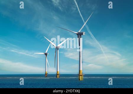 Trois éoliennes offshore debout dans la mer, avec un ciel bleu clair. Éoliennes en mer. Production d'énergie durable. Énergie verte. Banque D'Images