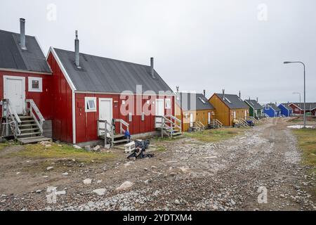 Rangée de maisons colorées le long d'une route de gravier sous un ciel nuageux, peuplement Inuit de l'Arctique éloigné Ittoqqortoormiit, Scoresbysund ou Scoresby Sund ou Gree Banque D'Images