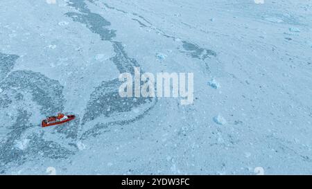 Aérienne d'un petit bateau flottant entre les glaces en dessous du glacier Eqi, ouest du Groenland, Danemark, régions polaires Banque D'Images