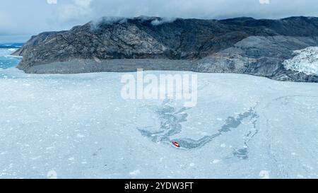 Aérienne d'un petit bateau flottant entre les glaces en dessous du glacier Eqi, ouest du Groenland, Danemark, régions polaires Banque D'Images