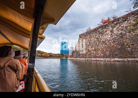 Vue depuis un bateau traditionnel sur les douves et les murs du château d'Osaka en automne avec des visiteurs visitant Osaka, Honshu, Japon, Asie Banque D'Images