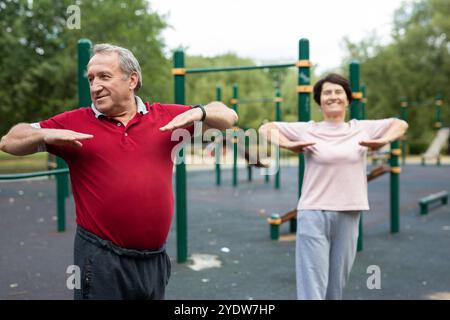 Heureux et en bonne santé. Couple de famille mature en vêtements de sport faisant de la gymnastique ensemble à la salle de gym extérieure. Homme et femme Banque D'Images