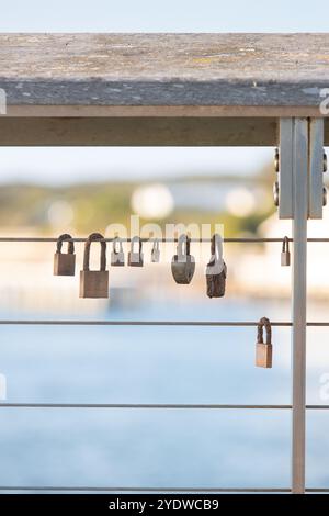 Groupe de serrures altérées sur une clôture métallique avec vue floue sur la plage Banque D'Images