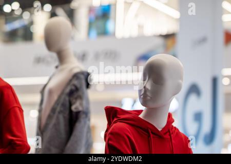 Dans un magasin, il y a un mannequin habillé d'un sweat à capuche rouge saisissant, mettant en valeur un design de mode tendance qui capte l'attention sans effort Banque D'Images