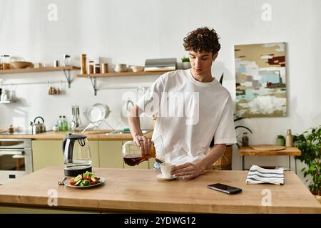 Le beau jeune homme verse du café fraîchement infusé dans une tasse tout en savourant son petit déjeuner à la maison. Banque D'Images