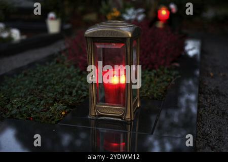 Lanterne grave avec bougie allumée sur une tombe au crépuscule Banque D'Images