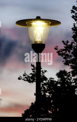 Un lampadaire brillant à l'ancienne contre un ciel rouge du soir Banque D'Images