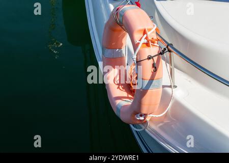 Bouée de sauvetage orange avec des cordes est attachée à une rampe de bateau chromée, offrant un sentiment de sécurité pour les passagers par une journée ensoleillée Banque D'Images