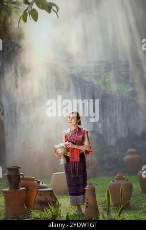 Jeune femme en vêtements traditionnels lao debout parmi des pots en argile dans un paysage brumeux, Laos Banque D'Images