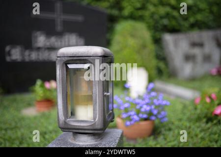 Lanterne grave sur une tombe avec des fleurs et de la pierre tombale dans un fond flou Banque D'Images