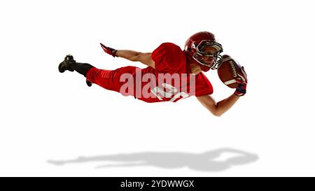 Homme déterminé, joueur de football américain en mouvement pendant le jeu intense, attraper la balle dans le milieu des airs et tomber, isolé sur fond blanc Banque D'Images