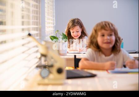 Enfants assis au bureau dans la salle de classe et test d'écriture. Les élèves écrivent dans un carnet pendant la leçon en classe. Banque D'Images