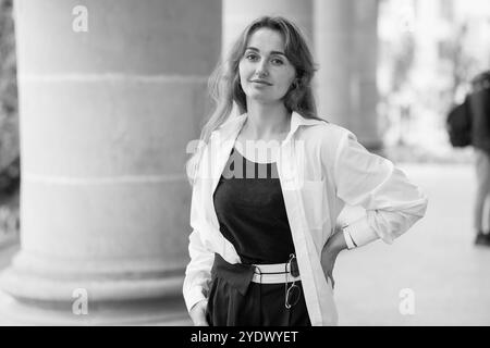 Portrait élégant d'une jeune femme dans une tenue élégante contre un fond architectural classique. Banque D'Images