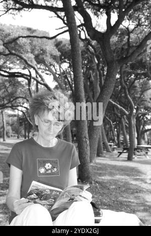 Femme âgée caucasienne, de 50 à 55 ans, lisant une brochure de voyage tout en se relaxant au Myrtle Beach State Park, Caroline du Sud, États-Unis. Banque D'Images