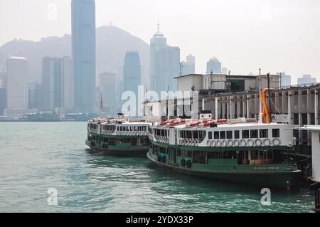 Hong Kong, Chine - 27 avril 2009 : deux ferries amarrés à l'embarcadère avec l'horizon de la ville en arrière-plan. Banque D'Images