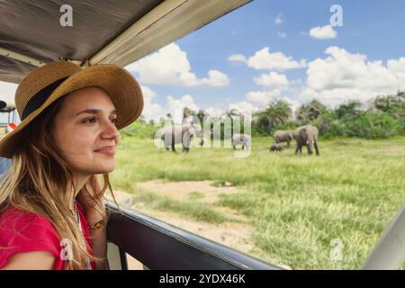 Une jeune femme découvre la nature africaine en voiture avec un safari Tanzanie à toit ouvert. Une fille caucasienne portant un chapeau regarde les animaux dans la savane. Le concept Banque D'Images