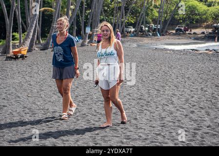 Cette charmante image capture une mère et sa fille se promenant main dans la main le long des rives spectaculaires de Punalu'u Beach à Hawaï. Banque D'Images