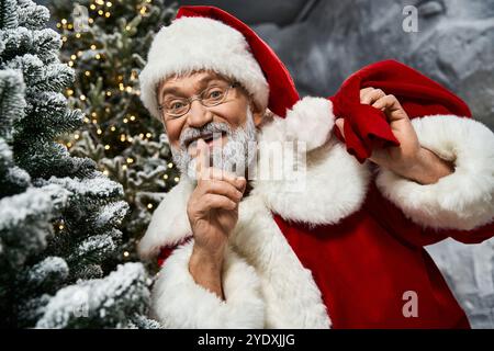 Un père Noël joyeux avec un sourire étincelant murmure un secret au milieu des pins enneigés Banque D'Images