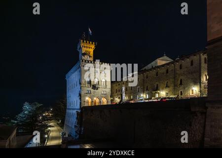 La Piazza del Comune à Saint-Marin la nuit. L'hôtel de ville historique (Palazzo Pubblico) avec son impressionnant clocher peut être vu au premier plan. Les bâtiments en pierre environnants sont éclairés et donnent à la scène une atmosphère particulière. La nuit donne à la ville un caractère calme et pittoresque. Piazza della Libertà, Città di San Marino, Saint-Marin Banque D'Images