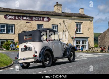 Voitures dans le rallye de voitures anciennes Beamish Relability 2024 passant devant le Rose and Crown Hotel à Bainbridge, Yorkshire Dales, Royaume-Uni. Banque D'Images