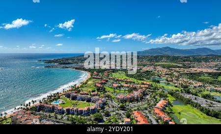 Vue aérienne de Palmas del Mar, Porto Rico, Une station balnéaire de la côte sud avec une végétation luxuriante, des terrains de golf, la côte rencontrant l'océan et des collines ondoyantes. Banque D'Images