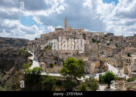 Nichée sur une colline rocheuse, Matera met en valeur son quartier historique de Sassi avec d'anciens bâtiments en pierre et des rues sinueuses, baignées de soleil doré. Banque D'Images