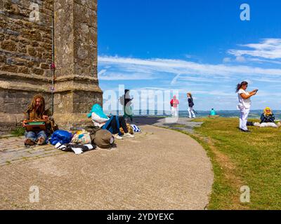Touristes se relaxant à côté de la tour de l'église St Michael sur Glastonbury Tor en été Somerset Angleterre Royaume-Uni Banque D'Images