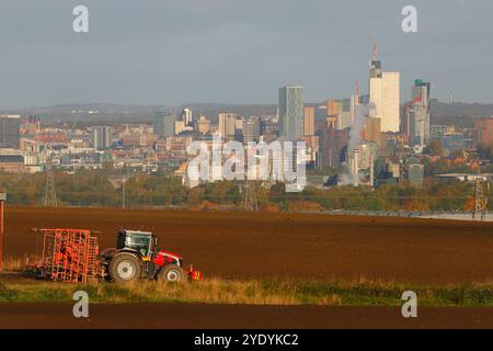 Agriculteurs labourant les champs avec le centre-ville de Leeds comme toile de fond Banque D'Images