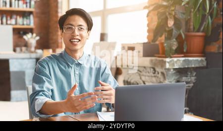 Un gars asiatique heureux partageant ses idées avec ses collègues Banque D'Images