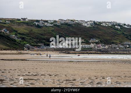 Surfeurs et nageurs sur la plage de Sennen Cove dans l'ouest de Cornwall, Angleterre. Banque D'Images