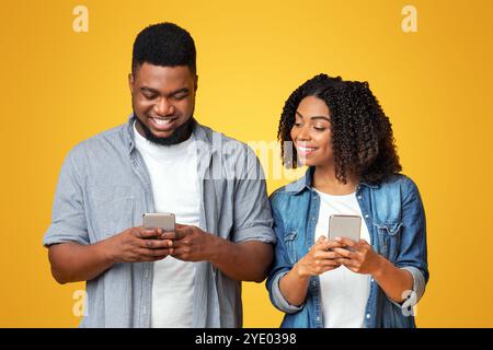 Curieuse petite amie noire qui s'épluche dans le smartphone de mon ami, essayant de lire des messages Banque D'Images