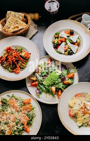 Salades gourmandes avec divers ingrédients dont avocat, feta, légumes grillés et saumon Banque D'Images