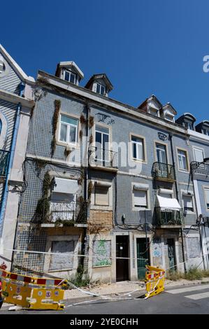 Un bâtiment de tuiles condamné à Alfama montre des signes d'âge et de décomposition urbaine, avec des azulejos bleus éclatants contrastant avec les murs usés Banque D'Images