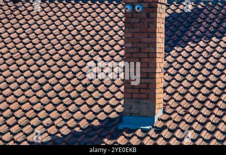 Cheminée de brique sur le toit : texture et ombres dans le détail architectural Banque D'Images