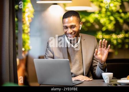 Homme d'affaires noir souriant faisant des appels vidéo à la famille Banque D'Images