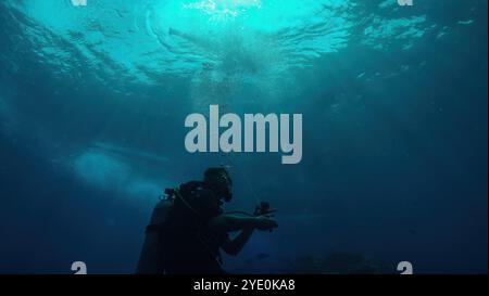 Plongeur explore l'océan bleu profond, en utilisant un boîtier de caméra sous-marin pour capturer la beauté de la vie marine, créant des photogra sous-marins à couper le souffle Banque D'Images